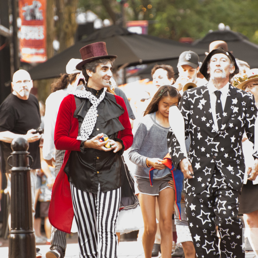 The Mayor wears a top hat, stiped pants and a red waistcoat and marches next to a man wearing a star print suit