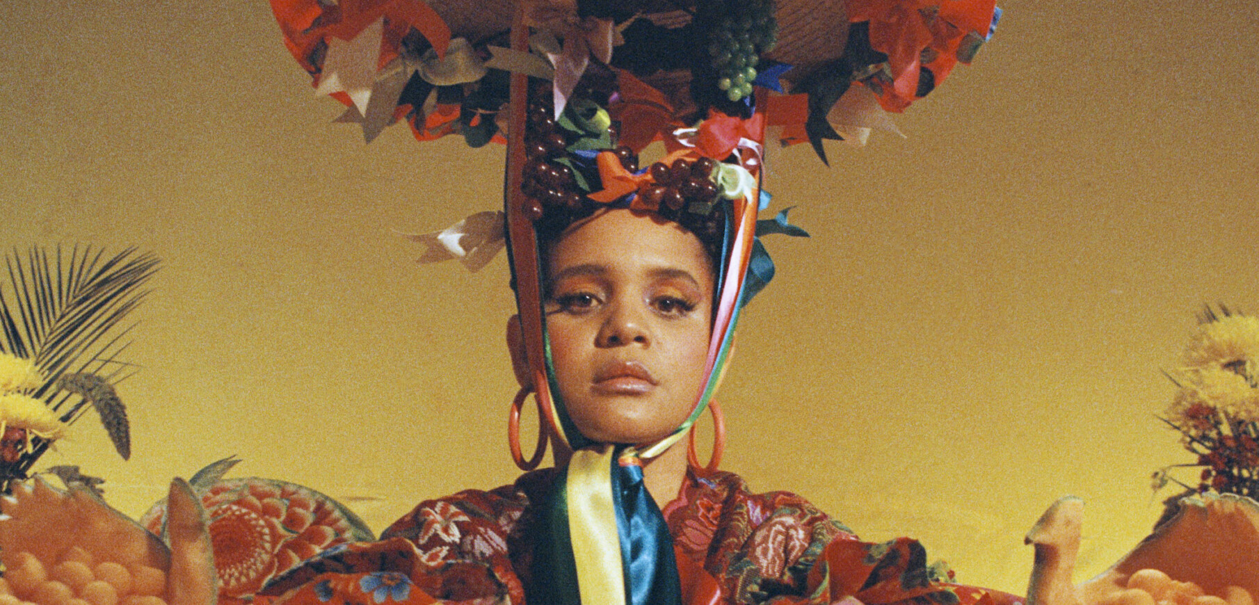 a medium skinned woman wears an elaborate colorful headdress