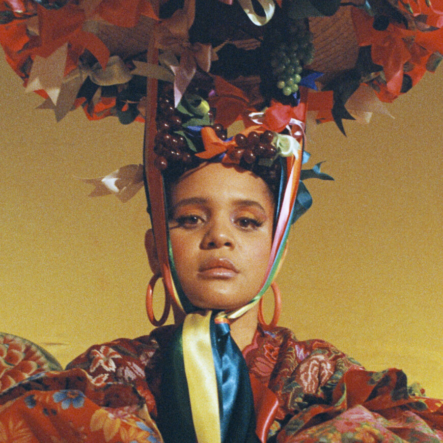 a medium skinned woman wears an elaborate colorful headdress