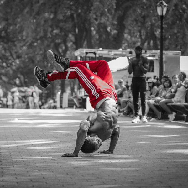 A man breakdancing in color against a black and white background.