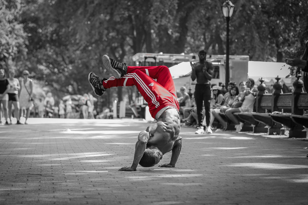 A man breakdancing in color against a black and white background.