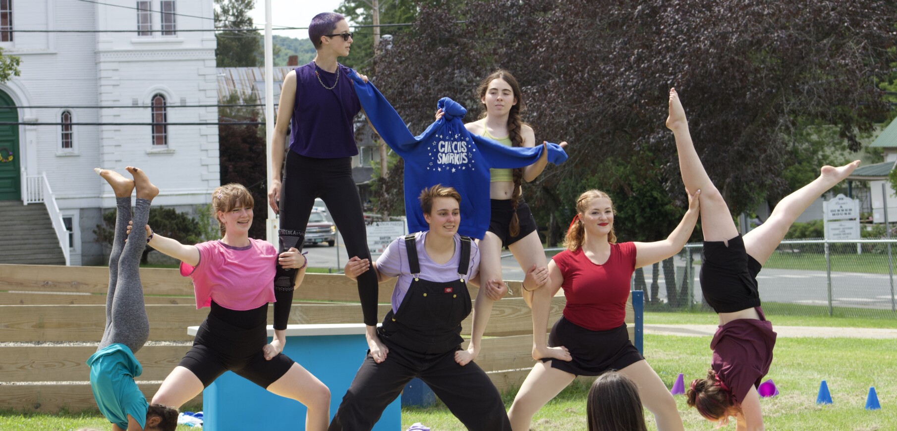 Young circus performers form an alignment outdoors.